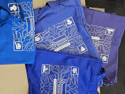 A stack of colored bags in blue and purple features a white graphic design of circuit patterns. The bags display the SEGGER logo and the phrase "The Embedded Experts," along with various icons representing technology and embedded systems.