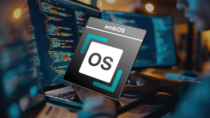 A close-up of a person's hands typing on a laptop, with computer code visible on the screen. An overlay features the logo for "embOS," showing the letters "OS" within a square and bordered by design elements, suggesting a focus on operating system development.