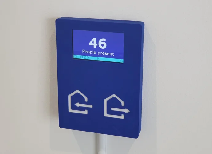 Blue display panel showing "46 People present" with two directional icons (left and right arrows) below the screen.