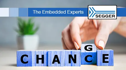 A hand is adjusting lettered blocks spelling "CHANCE" on a table. In the background, there's a small green plant. The top of the image includes the text "The Embedded Experts" and a logo for SEGGER.