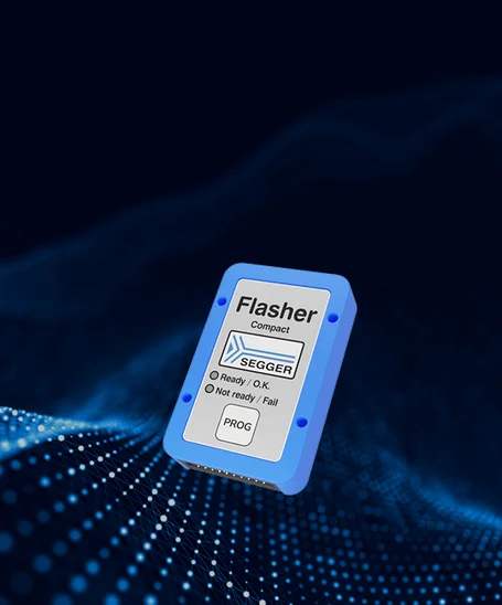 A compact SEGGER Flasher device is displayed, featuring a label with "Flasher" and "Compact" prominently. It includes indicators for status: "Ready / OK" and "Not ready / Fail," along with a "PROG" button. The background is dark with a subtle abstract pattern.