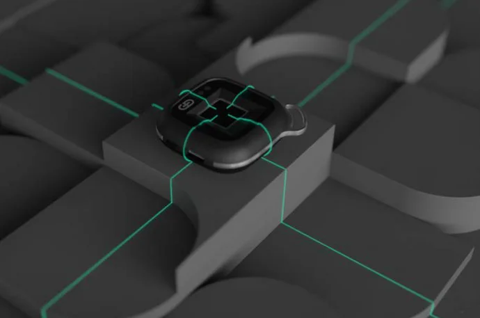 A sleek, black device is positioned on a textured, dark surface featuring geometric shapes. Subtle green lines intersect across the surface, highlighting the device, which has a small screen and buttons, suggesting a modern and tech-oriented design.