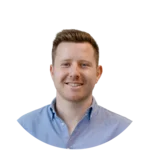 A smiling man with short brown hair is wearing a light blue button-up shirt. He is facing the camera against a neutral background, exuding a friendly and approachable demeanor.
