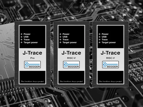 Three J-Trace devices displayed on a circuit board background. Each device has a black and silver design with labels: "J-Trace Pro" and "J-Trace RISC-V," indicating features like Power, USB, Trace, and Target power. The SEGGER logo is also present.