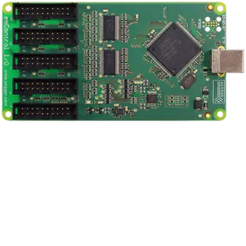 A top-down view of a green circuit board featuring multiple connector pins, integrated circuits, and a USB port on the right side. The board is labeled "emControl I/O" and includes various electronic components typical of a microcontroller interface.