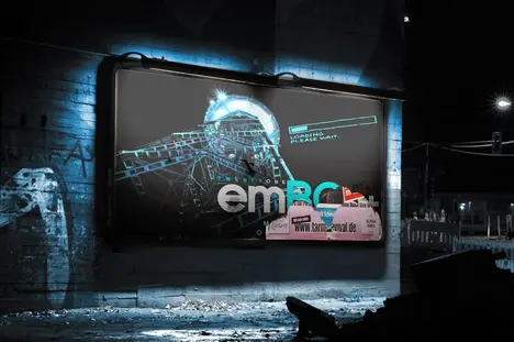 A digital billboard in a dark urban setting displays the text "loading, please wait" alongside the word "emRC" in bold letters. The background features a stylized graphic of a ferris wheel. The overall atmosphere appears gritty and industrial.