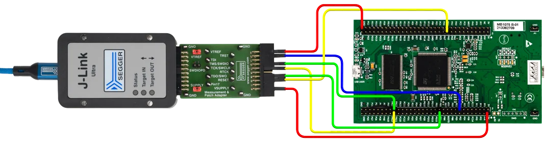 Image shows a J-Link Ultra programmer connected to a patch adapter and a green circuit board. Color-coded wires connect various ports, indicating connections for power and data transfer between the programmer and the circuit board components.