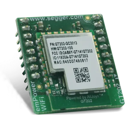 A small green circuit board featuring a microchip at the center, surrounded by gold pins and electronic components. The chip includes identification details such as a part number and a QR code, indicating it is designed for Wi-Fi connectivity.