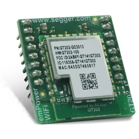 A small green circuit board featuring a microchip at the center, surrounded by gold pins and electronic components. The chip includes identification details such as a part number and a QR code, indicating it is designed for Wi-Fi connectivity.