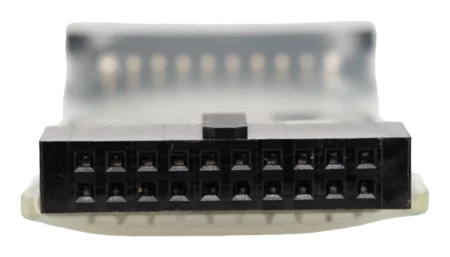 Close-up view of a black electrical connector with multiple pin ports arranged in two rows, mounted on a translucent backing. The focus is on the configuration and design of the connector.