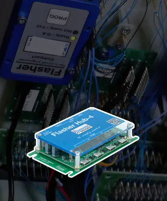 The image features a blue electronic circuit board labeled "Flasher Hub 4," prominently displayed with several connection ports on its surface. Behind it, additional circuit boards and tangled wires are visible, indicating a complex electronic setup.