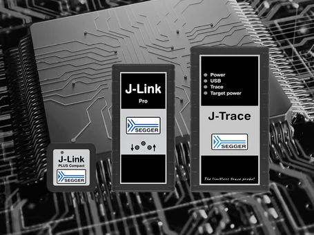 Three SEGGER debugging tools are displayed on a circuit board background. From left to right: J-Link PLUS Compact, J-Link Pro, and J-Trace. Each device features key labels related to power, USB, trace capabilities, and target power. The overall image showcases high-tech electronics.