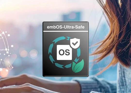 A close-up of a person's hand resting on a laptop keyboard, with a soft-focus background featuring a cityscape and a graphic displaying the "embOS-Ultra-Safe" logo. The logo includes a shield, a circular arrow symbol, and a green leaf, indicating safety and sustainability in software.