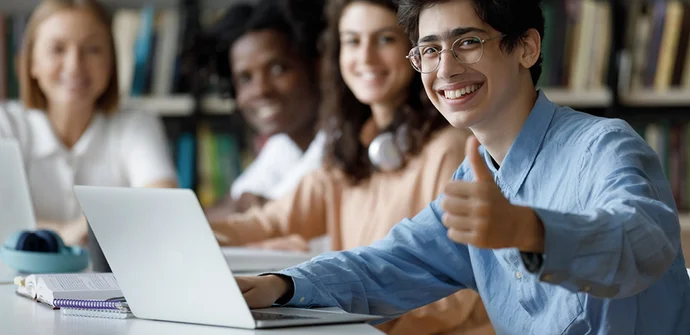 Enjoy free software tools for embedded system development with SEGGER's Friendly license Student in front of laptop, giving a thumbs up, several students in background