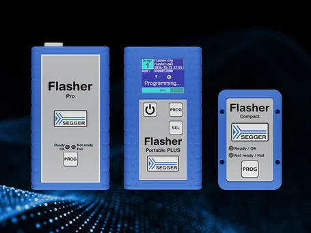 Three SEGGER flasher devices are displayed on a dark, textured background. From left to right: Flasher Pro with a plain interface, Flasher Portable PLUS featuring a color screen displaying programming progress, and Flasher Compact with basic status indicators. All devices are blue and labeled clearly.