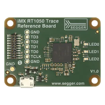 Image of the iMX RT1050 Trace Reference Board featuring various electronic components. The board includes labeled pins, a micro USB connector, and three LEDs. It has a dark green background with white text indicating the brand, model, and version.